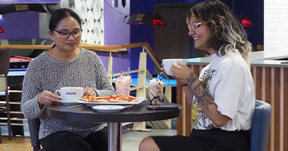 Two women enjoying pizza, coffee and milkshakes