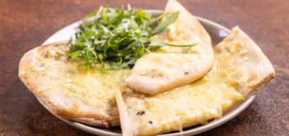 Cheese & Rocket Stone Banked Garlic Flat Bread served with salad on a plate