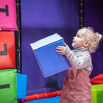 Young girl holding a small box and playing in soft play area at namco funscape