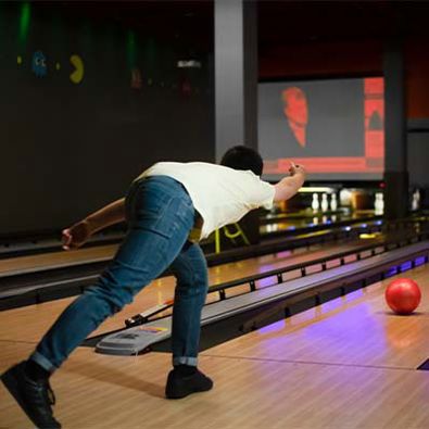 Male throwing a red bowling ball down a bowling lane