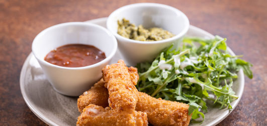 Chicken tenders served on a plate with salad and two dipping sauces