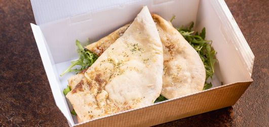 Garlic & Rocket Stone Baked Flat Bread served with salad in a takeaway box