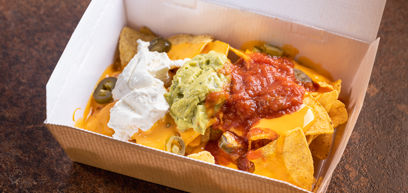 Mexican Nachos served with jalapenos, melted cheese, sour cream and guacamole in a takeaway box