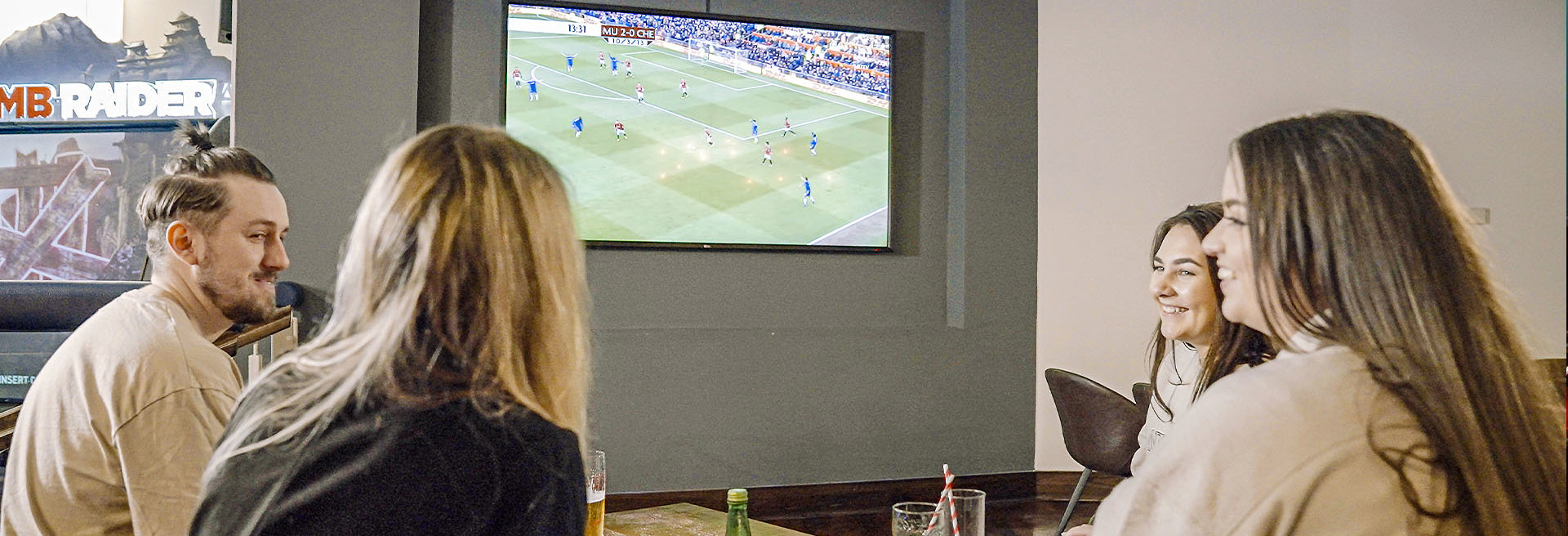 Group of friends having a drink and socialising whilst watching football 