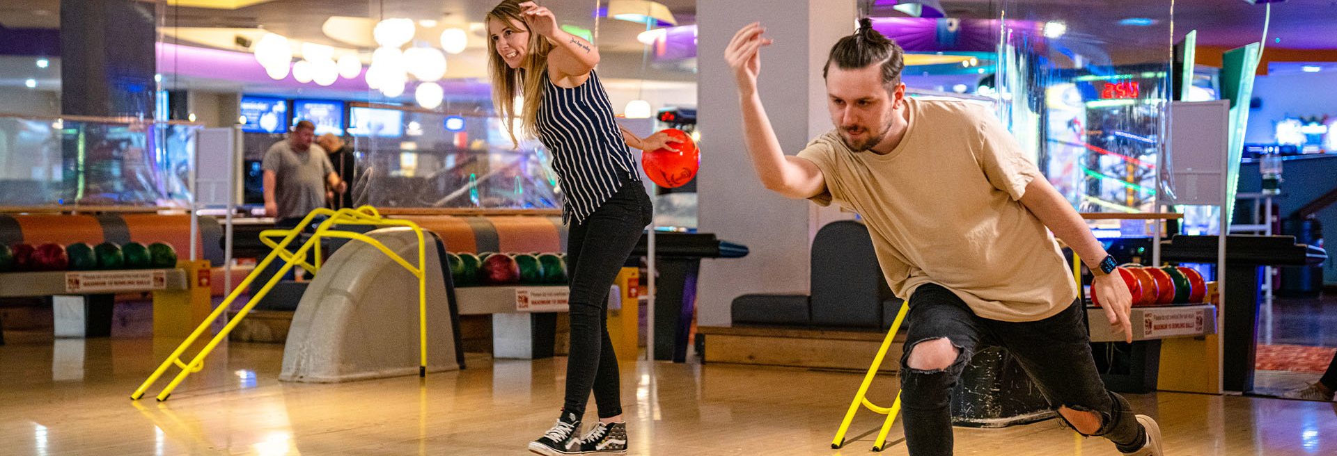 Girl and boy throwing bowling ball down a bowling lane