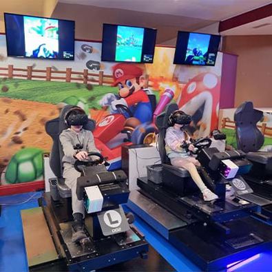 Girl and boy wearing virtual reality headsets whilst playing mario kart arcade game