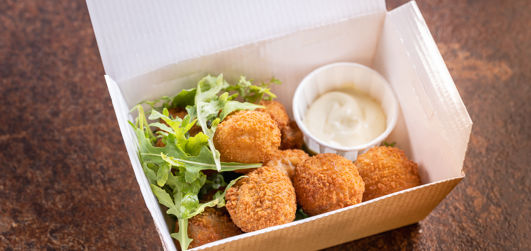 Classic breaded mushrooms with salad and dipping sauce in a takeaway box
