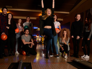 Group of friends cheering whilst playing a game of bowling