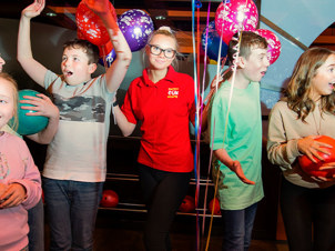 Cheerful group of children celebrating at a birthday party, surrounded by baloons and decorations, smiles, and excitement