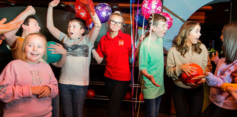 Cheerful group of children celebrating at a birthday party, surrounded by baloons and decorations, smiles, and excitement