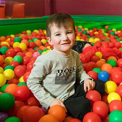 Young boy smiling in a colourful ball pit