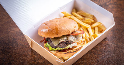 Beef burger with bacon and chips in a takeaway box