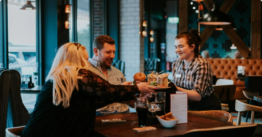 Couple being served food at Clyde's Bar and Grill by staff member