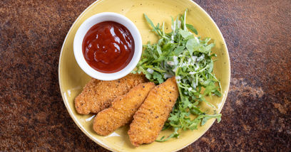 Chicken pieces served on a plate with ketchup and salad