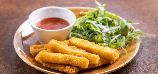 Fish fingers served on a plate with salad and a dipping sauce
