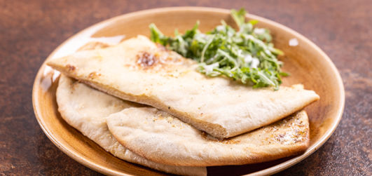 Garlic & Rocket Stone Baked Flat Bread served with salad on a plate
