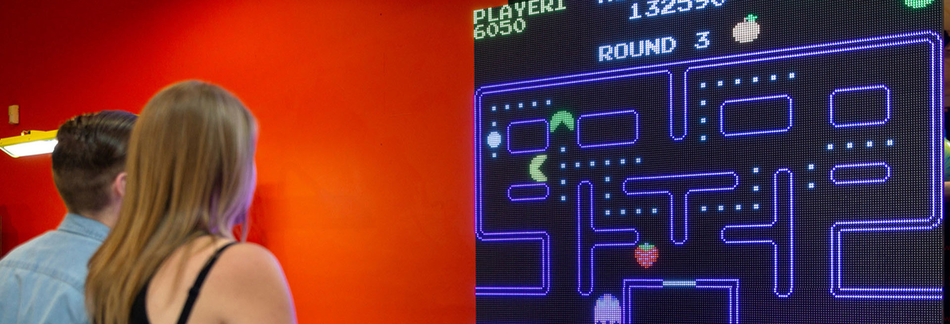 Girl and boy playing pacman arcade game